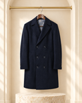 Navy double-breasted wool-blend overcoat on a wooden hanger suspended from a gold rail in a cream marble boutique setting